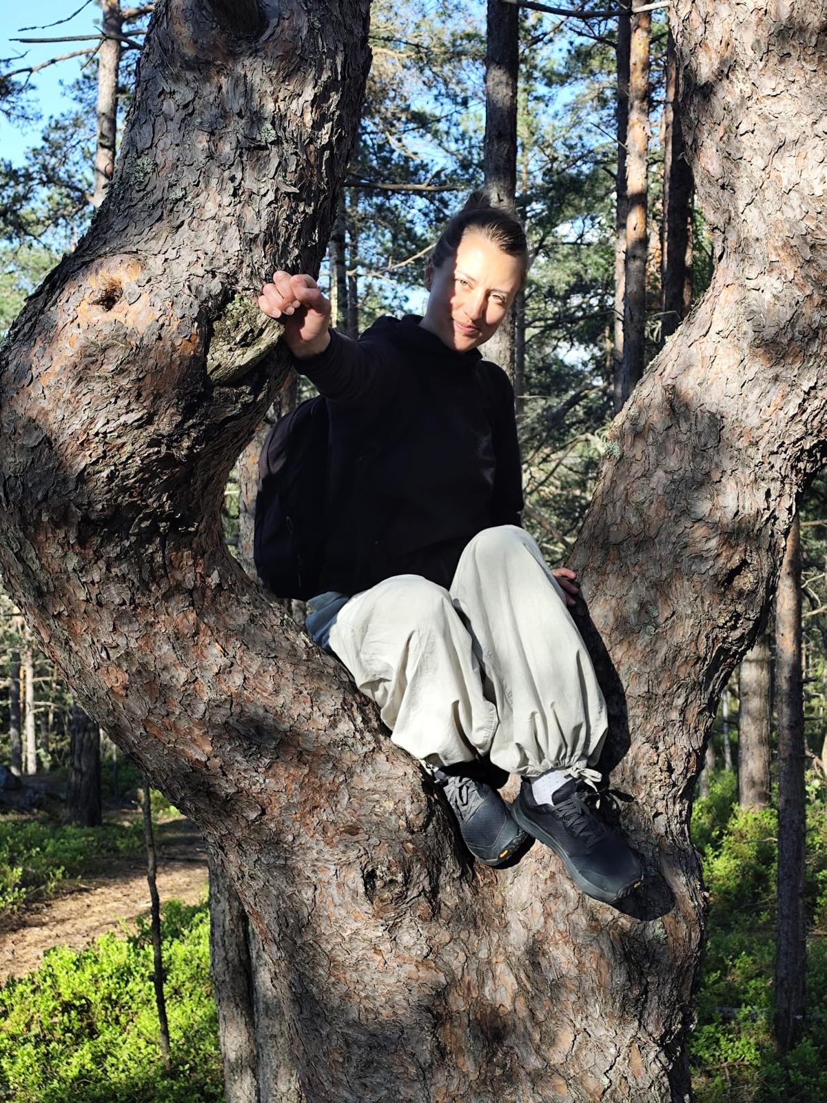Louise Emterfors sitter i en tall i skogen